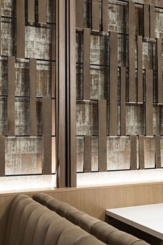 the interior of a restaurant with wooden walls and leather seats, along with large windows that have decorative panels on them