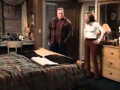 a man and woman standing in a bedroom