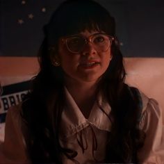 a woman wearing glasses sitting down in front of a wall with stars on the walls