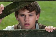 a young man peeking over a wooden fence