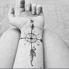 a black and white photo of a person's arm with a compass tattoo on it