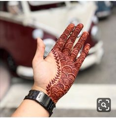 a woman's hand with hennap on it, in front of a car