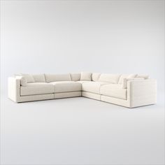 a large white sectional couch sitting on top of a white floor next to a wall