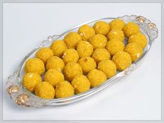 a glass dish filled with lots of small yellow food items on top of a white table