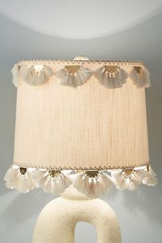 a lamp that is sitting on top of a table next to a light fixture with tassels around it