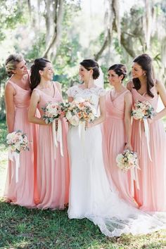 a group of women standing next to each other wearing dresses and holding bouquets in their hands