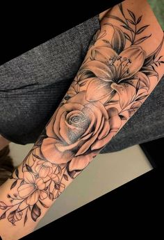 a woman's arm with flowers and leaves on it