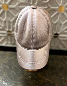 a silver baseball cap sitting on top of a counter next to a white and gold wall