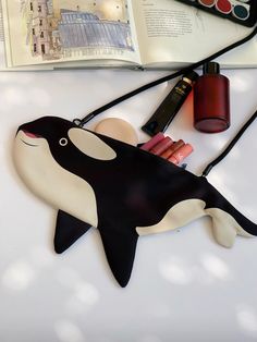 an orca whale shaped purse sitting on top of a table next to a book