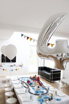 a party table with balloons, streamers and confetti on it in the middle of a room