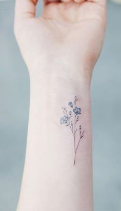 a small blue flower tattoo on the wrist