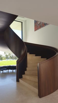 a spiral staircase in the middle of a room with large windows and wooden railings