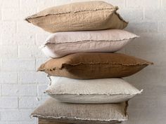 four pillows stacked on top of each other in front of a white brick wall,