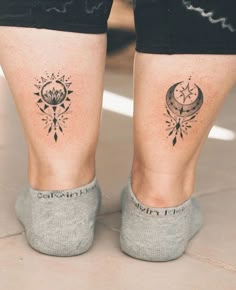 two people with tattoos on their legs are standing in front of each other's feet