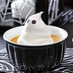 a bowl filled with whipped cream topped with a ghost face on it's head