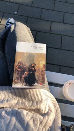 a book sitting on top of a white bench next to a person's legs