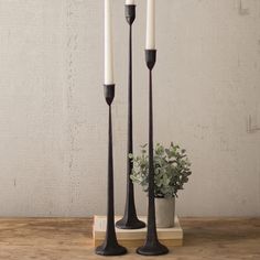 two black candles are sitting on a wooden table