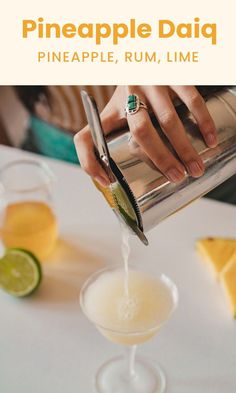 someone pouring pineapple daiquit into a glass with limes on the side