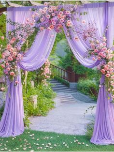 an outdoor wedding ceremony with purple draping and pink flowers on the arbors