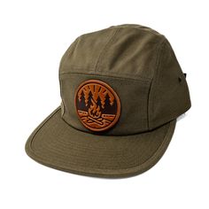 Get Fired Up for Adventure with this Campfire Cap! The patch on this hat features a classic campfire scene, capturing the timeless allure of the great outdoors. It's a simple yet evocative image: two logs ablaze with flames reaching upwards, cradled by a circle that hints at the unity and completeness of nature. The trees standing sentinel on either side anchor the scene in the wild, calling to mind the serenity of the woods and the simple pleasures of a fireside chat under the stars. Each cap i