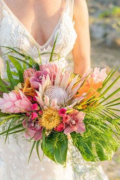 a bride holding a bouquet of flowers in her hand and wearing a wedding dress with lace