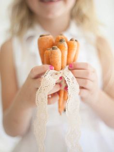 a woman holding four baby carrots in her hands