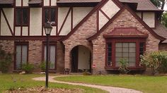 an old brick house with red trim and arched windows, along with a stone path leading to the front door