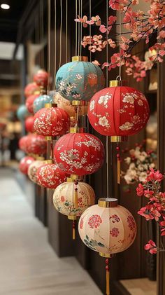 red and blue lanterns hanging from the ceiling in front of a building with flowers on it