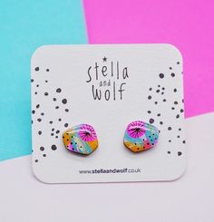 a pair of colorful earrings sitting on top of a white and blue card with the words stella and wolf