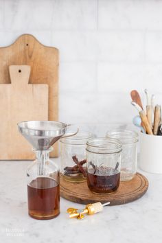 three jars filled with liquid sitting on top of a counter next to utensils