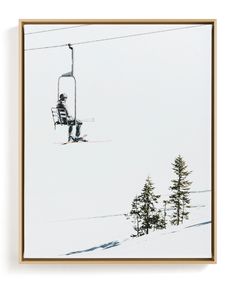 a man riding a ski lift down the side of a snow covered slope next to trees