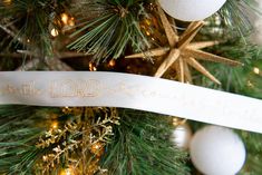 a close up of a christmas tree decorated with ornaments and ribbon that says little lord