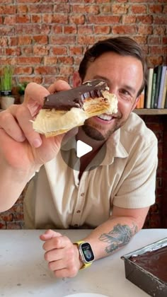 a man eating a chocolate and banana sandwich at a table in front of a brick wall