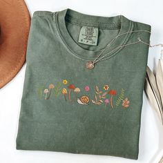 Comfort Colors Embroidered Tshirt Mushroom and Wildflower Tshirt Cute Snail  shirt, Flower Boho Shirt, Fall Tshirt, MADE IN USA PRODUCT INFORMATION:  6.1 oz./yd² (US), 10 oz/L yd (CA), 100% ring-spun cotton, 30 singles Garment dyed for that lived in feel and almost no shrinkage at home. Soft ring-spun cotton fabric with 100% cotton threads Relaxed fit Topstitched, classic width, rib collar Shoulder to shoulder twill tape Signature twill label IE Embroided T Shirts, Casual Green Tops With Mushroom Print, Spring Mushroom Design Short Sleeve Tops, Summer Cotton Tops With Mushroom Design, Cute Green Embroidered Tops, Casual Crew Neck Shirt With Mushroom Print, Casual Cotton Tops With Mushroom Print, Cotton Crew Neck Tops With Mushroom Print, Cotton Short Sleeve Tops With Mushroom Design