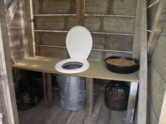 a toilet sitting on top of a wooden shelf next to a trash can and bin