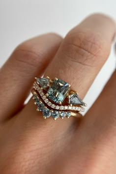 a woman's hand with a ring on it that has three different colored stones