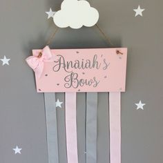 a wooden sign hanging from the side of a wall with stars and clouds on it