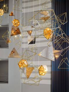 an art installation with gold geometric shapes hanging from it's sides and lights on the ceiling