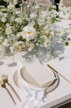 a table set with white flowers and silverware