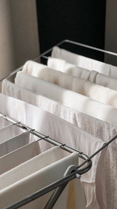 several folded towels are hanging on a clothes line in a room with black walls and white linens