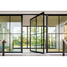 an open glass door in front of a white wall and wooden stairs with black handrails