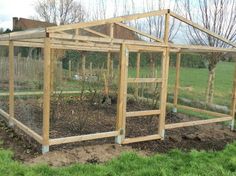 a small wooden greenhouse sitting in the middle of a field with dirt and grass around it