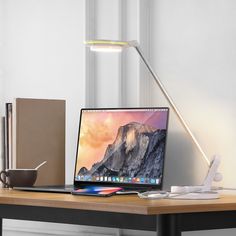 a laptop computer sitting on top of a wooden desk next to a lamp and mouse