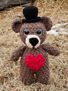 a crocheted teddy bear with a heart on it's chest sitting in the grass