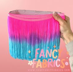 a person holding up a pink and blue fringe