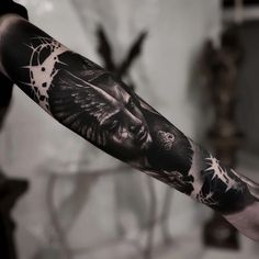 a man's arm with an owl and skull tattoo on it