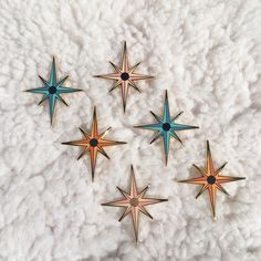 five star brooches sitting on top of a pile of white fluffy material in the shape of stars