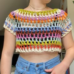 a close up of a person wearing a crochet top and denim shorts with her hands on her hips