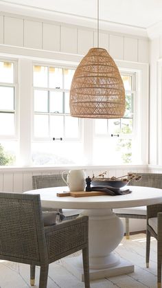 a dining room table with chairs and a basket light fixture hanging from the ceiling over it