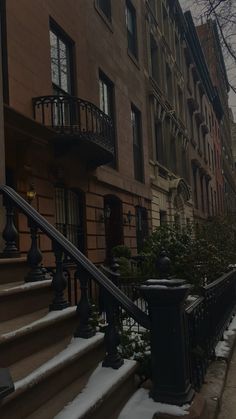 snow covers the sidewalk and steps in front of brownstone apartment buildings